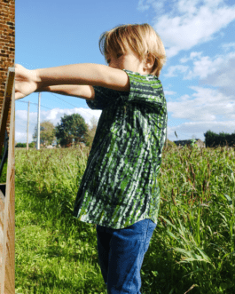 chemise verte à motifs abstraits, portée par un jeune garçon tourné de profil qui tend les mains devant lui