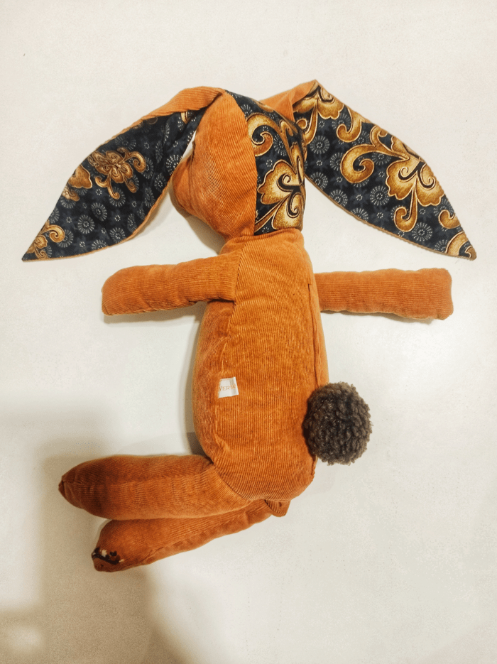 lapin en peluche de couleur orange citrouille, vue de 3/4 dos