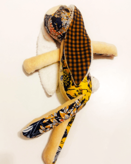 doudou en forme de lapin, il est en tissu wax et en velours côtelé beige; ses oreilles sont contrastées en tissu à petits carreaux marrons et noirs