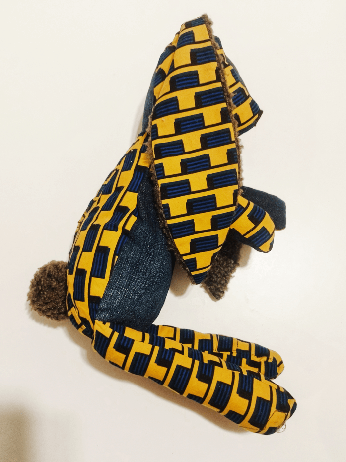 doudou lapin en wax africain jaune et bleu, le motif est un damier, le lapin a une queue en pompon marron qui contraste avec le corps, le dessus de la tête est en denim