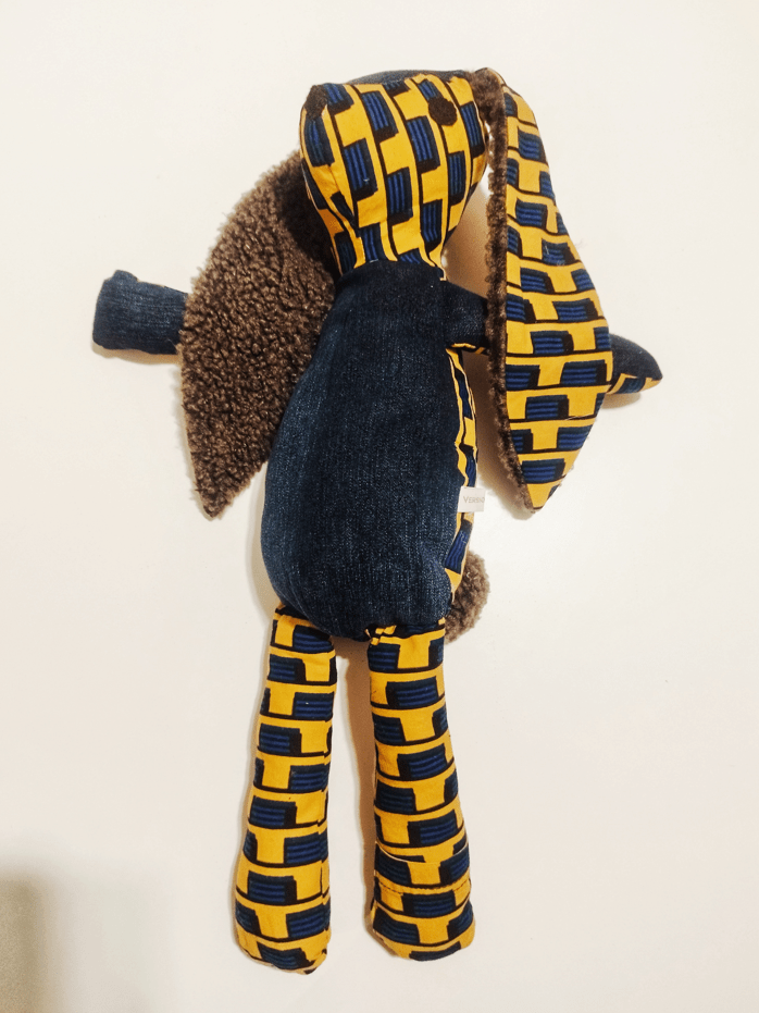 Doudou lapin en Wax africain représentant un damier bleu sur fond jaune. Il s'agit d'un lapin en tissu avec des grandes oreilles doublées de tissu duveteux. le ventre et les pattes avant sont en Denim