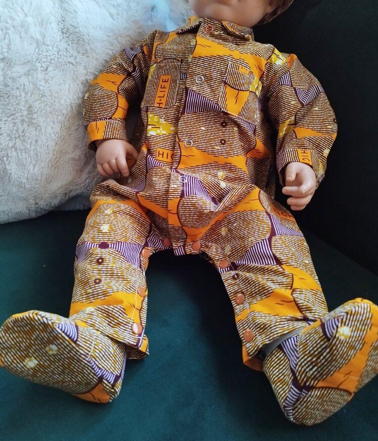 mannequin bébé assis, porte un ensemble combinaison en pagne orange