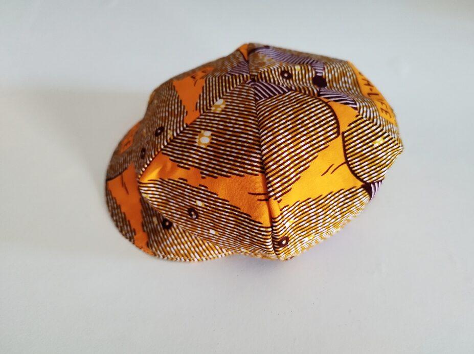 casquette forme "gavroche" en wax pour bébé, elle est multicolore avec une dominance d'orange vue de profil