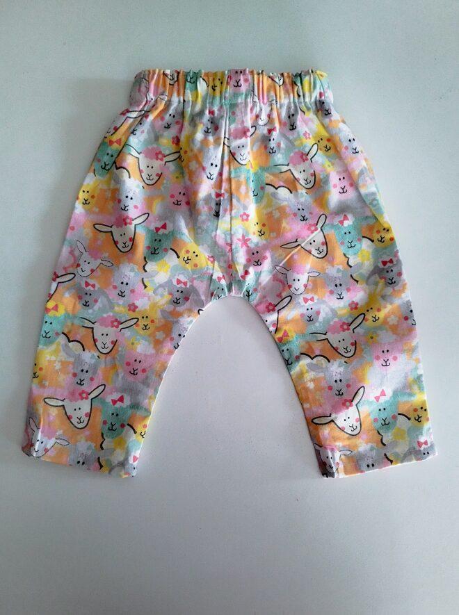 pantalon bébé imprimé à motif de moutons blanc, le fond du dessin est jaune, bleu et vert, vue de dos