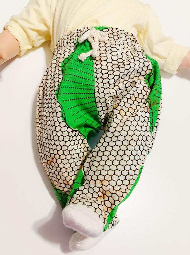pantalon en wax pour bébé vert et beige porté jambes croisées