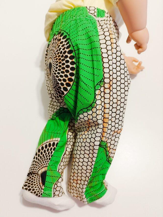 Pantalon pour bébé en wax vert et beige porté de profil