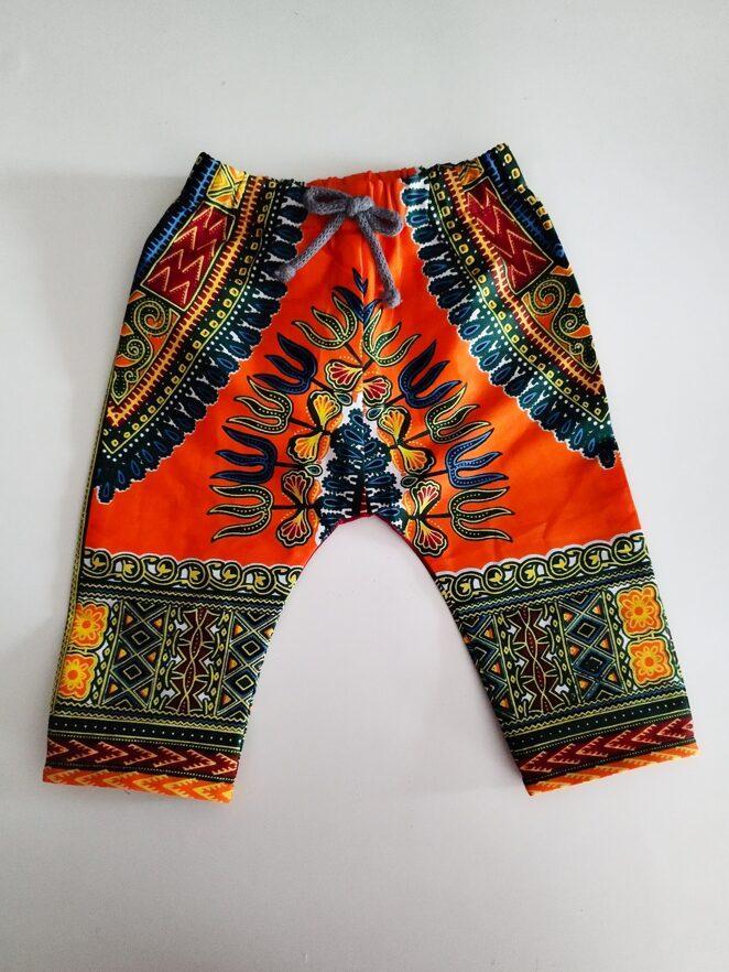 pantalon en coton posé à plat à motif multicolores bleu et bordeaux sur fond orange brillant
