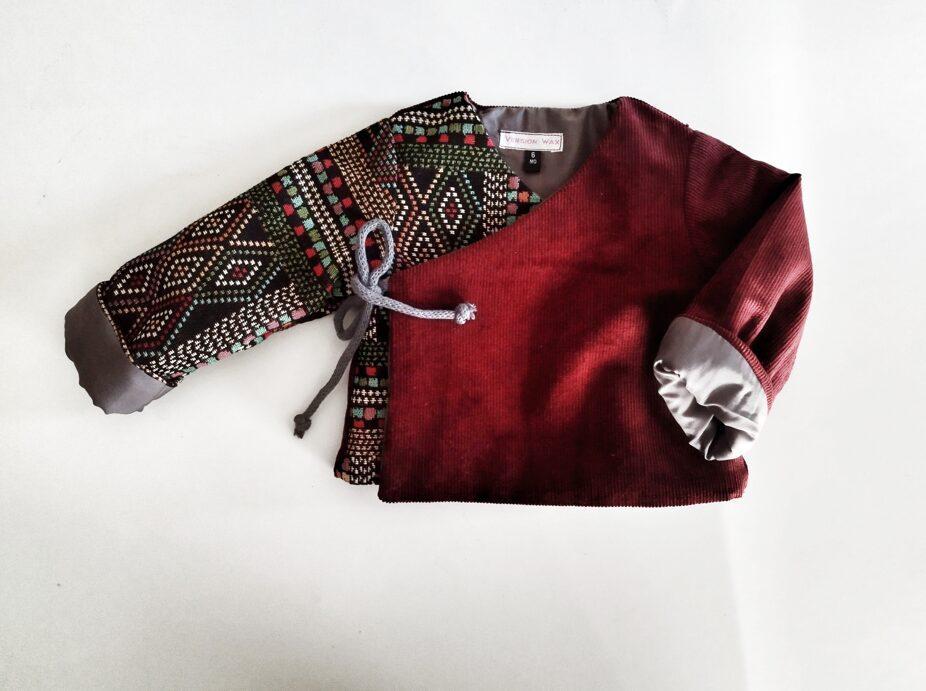 Veste mixte croisée nouée sur le côté pour bébé. il est en velours à fines côtes rouge bordeaux et jacquard rayé