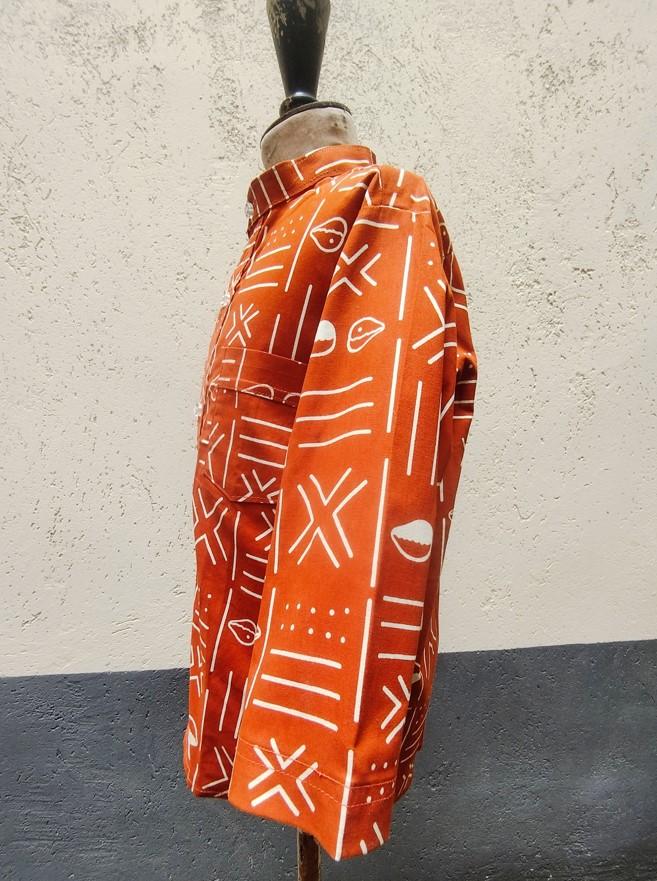 Chemise pour garçon à motif Bogolan de couleur brique et écru porté sur mannequin de bois