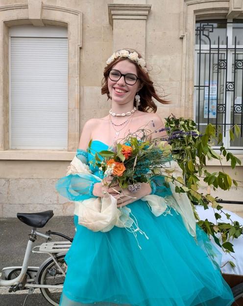 jeune fille en robe bleue portant un bouquet de fleurs