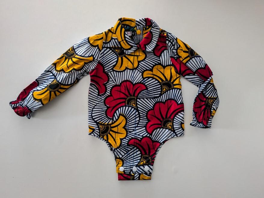 body en coton wax imprimé fleurs de mariage, rouge et orange sur fond blanc pour bébé fille; il a des manches longues et un col claudine