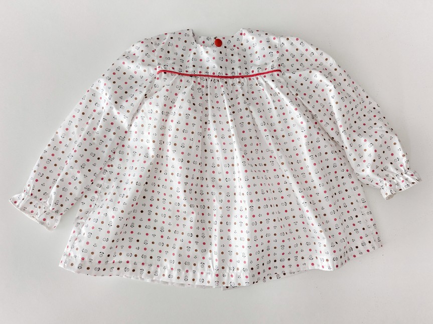robe pour bébé, elle est blanche avec des motifs rouges