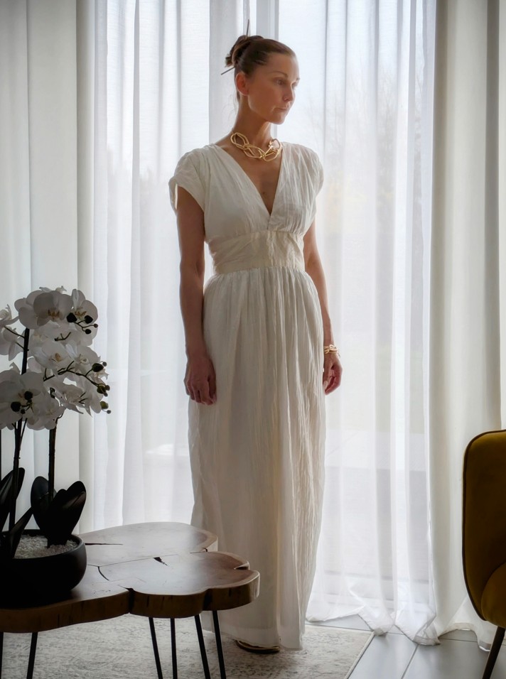 femme debout devant une fenêtre en robe blanche