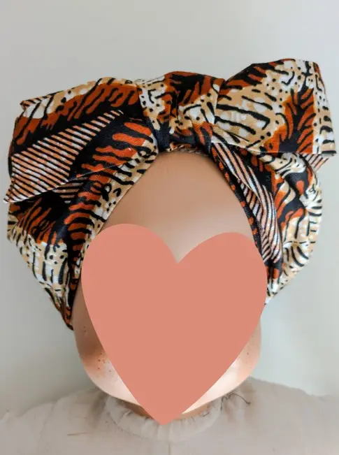 bonnet en wax pour bébé de couleur marron et beige, il ressemble à un fichu attaché sur la tête