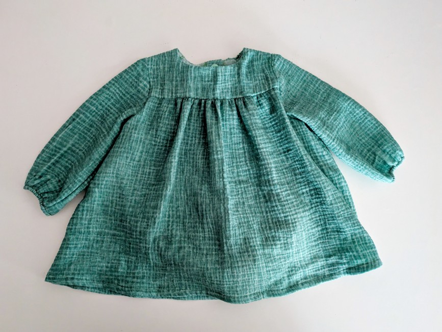 Robe pour bébé de couleur verte, elle est ample et a des manches longues